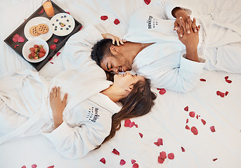 Image showing Young couple love on bed, with flowers and healthy snack on tray while on holiday. Man and woman, romance together in bedroom with roses and food, smile on valentines day trip or anniversary vacation