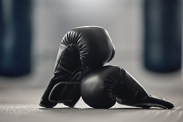 Image showing Boxing gloves on the floor of a gym after exercise, training and workout. Pair of sport handwear or equipment on the ground after fighting match, practice or punching in a competitive sports club