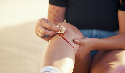 Image showing Knee injury and person cleaning blood wound with tissue to stop bleeding for healing and recovery. Self care hygiene after accident with torn and sore skin on leg for infection prevention.