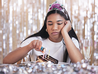 Image showing Sad, depression and angry woman at birthday celebration while lighting candle on cake. Lonely, depressed and frustrated female sitting at a party, fail and table with snack, decoration and tiara