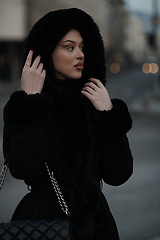 Image showing Muslim woman walking on an urban city street on a cold winter night wearing hijab