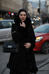 Image showing Muslim woman walking on an urban city street on a cold winter night wearing hijab