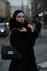 Image showing Muslim woman walking on an urban city street on a cold winter night wearing hijab