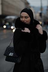 Image showing Muslim woman walking on an urban city street on a cold winter night wearing hijab