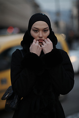 Image showing Muslim woman walking on an urban city street on a cold winter night wearing hijab