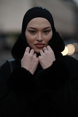 Image showing Muslim woman walking on an urban city street on a cold winter night wearing hijab