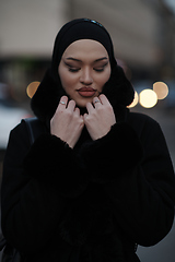 Image showing Muslim woman walking on an urban city street on a cold winter night wearing hijab