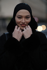 Image showing Muslim woman walking on an urban city street on a cold winter night wearing hijab