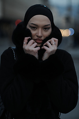 Image showing Muslim woman walking on an urban city street on a cold winter night wearing hijab