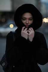 Image showing Muslim woman walking on an urban city street on a cold winter night wearing hijab