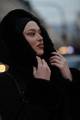 Image showing Muslim woman walking on an urban city street on a cold winter night wearing hijab