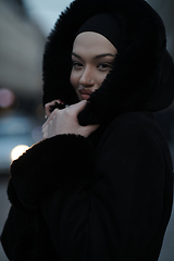 Image showing Muslim woman walking on an urban city street on a cold winter night wearing hijab