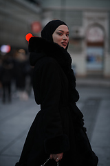 Image showing Muslim woman walking on an urban city street on a cold winter night wearing hijab