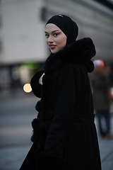 Image showing Muslim woman walking on an urban city street on a cold winter night wearing hijab