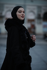 Image showing Muslim woman walking on an urban city street on a cold winter night wearing hijab