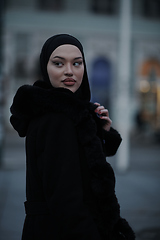 Image showing Muslim woman walking on an urban city street on a cold winter night wearing hijab