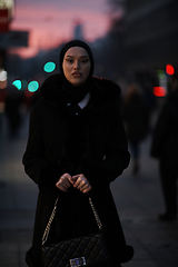 Image showing Muslim woman walking on an urban city street on a cold winter night wearing hijab