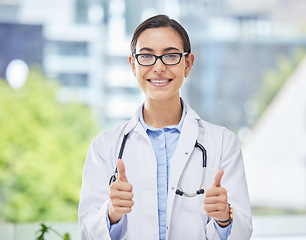 Image showing Portrait of a doctor showing thumbs up while standing in her office at the hospital. Happy, smile and professional healthcare worker doing a agreement gesture for a medical diagnosis in clinic.