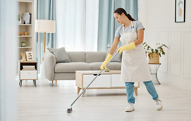 Image showing Woman working in a cleaning service mopping the living room floor of a modern home or apartment. Asian cleaner or housewife doing her job or housework to spring clean house for good hygiene lifestyle