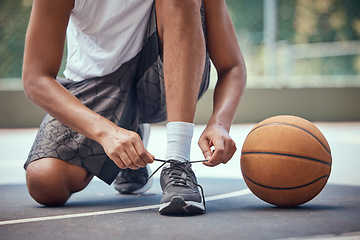 Image showing Shoes, basketball and sports with a man basket ball player tying his laces on a court before a game or match. Workout, fitness and exercise with a male athlete outside for health, wellness and cardio