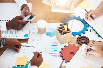 Image showing Hands, teamwork and planning with a marketing team working on a table full of paperwork, gears and graphs. Collaboration, synergy and strategy with a business group at work in their modern office