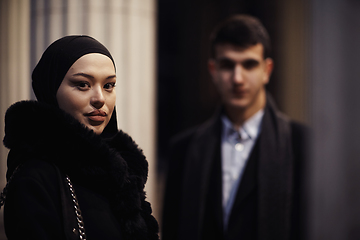 Image showing Happy multicultural business couple walking together outdoors in an urban city street at night near a jewelry shopping store window.