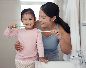 Image showing Children, dental and toothbrush with a girl and her mother brushing their teeth together in the bathroom of their home. Family, hygiene and oral with a woman and daughter practicing care and hygiene