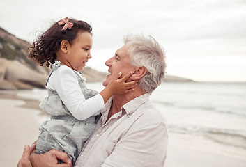 Image showing Family, beach and bonding with grandfather and grandchild hug, sharing a sweet moment in nature together. Young girl holding senior man, having fun, talking and enjoying a day outdoors at the ocean