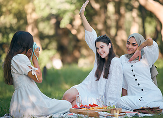 Image showing Friends, camera and photo on a picnic in a forest with food and drinks on green grass. Diversity, fun and happy women enjoy bonding together in nature with snacks while posing for a photo or picture