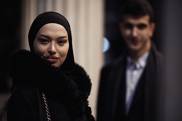 Image showing Happy multicultural business couple walking together outdoors in an urban city street at night near a jewelry shopping store window.