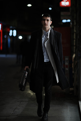 Image showing Smiling Meedle Eastern man walking down street near modern office building,