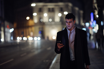 Image showing Smiling Meedle Eastern man walking down street near modern office building,