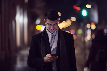 Image showing Smiling Meedle Eastern man walking down street near modern office building,