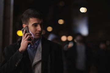 Image showing Smiling Meedle Eastern man walking down street near modern office building,