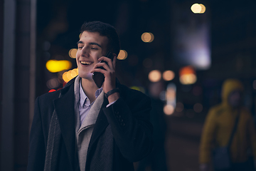 Image showing Smiling Meedle Eastern man walking down street near modern office building,