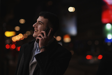 Image showing Smiling Meedle Eastern man walking down street near modern office building,