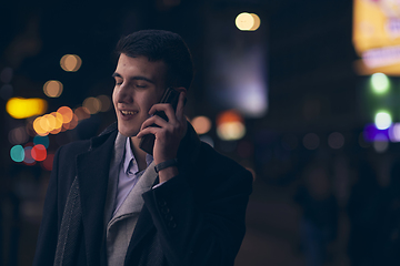 Image showing Smiling Meedle Eastern man walking down street near modern office building,