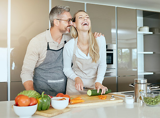 Image showing Couple in kitchen cooking together in their home, having fun and laughing. Middle aged man and woman cutting healthy vegetables and making food in their house. Smiling, happy and in love people