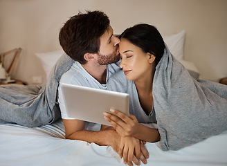 Image showing Couple, love and tablet for entertainment while lying in bed with a kiss on forehead while watching a movie, internet browsing and streaming service. Loving man and woman in bedroom with 5g network