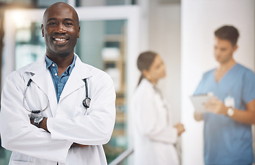 Image showing Doctor, healthcare and medicine with a man surgeon standing arms crossed in the hospital with his team in the background. Trust, insurance and care with a male health professional working in a clinic