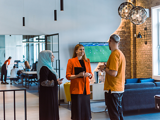 Image showing A group of young business colleagues, including a woman in a hijab, stands united in the modern corridor of a spacious startup coworking center, representing diversity and collaborative spirit