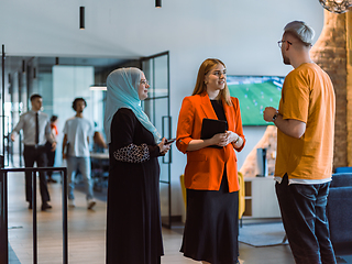 Image showing A group of young business colleagues, including a woman in a hijab, stands united in the modern corridor of a spacious startup coworking center, representing diversity and collaborative spirit