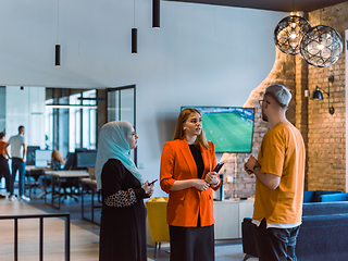 Image showing A group of young business colleagues, including a woman in a hijab, stands united in the modern corridor of a spacious startup coworking center, representing diversity and collaborative spirit