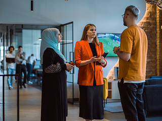 Image showing A group of young business colleagues, including a woman in a hijab, stands united in the modern corridor of a spacious startup coworking center, representing diversity and collaborative spirit