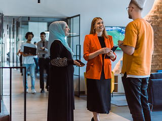 Image showing A group of young business colleagues, including a woman in a hijab, stands united in the modern corridor of a spacious startup coworking center, representing diversity and collaborative spirit