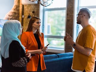 Image showing A group of young business colleagues, including a woman in a hijab, stands united in the modern corridor of a spacious startup coworking center, representing diversity and collaborative spirit