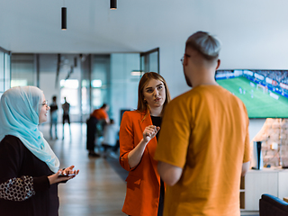 Image showing A group of young business colleagues, including a woman in a hijab, stands united in the modern corridor of a spacious startup coworking center, representing diversity and collaborative spirit