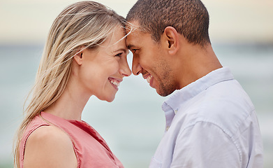 Image showing Portrait of couple at the beach with their forehead touching. Multiracial man and woman in relationship, happy, smiling and in love on vacation. Bonding, love and quality time together