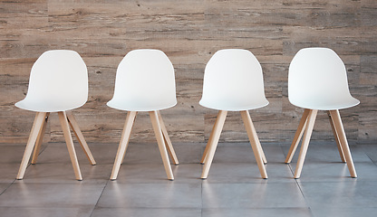 Image showing Hiring staff recruitment drive, interview waiting room and four white office chairs in empty wood wall background. Business opportunity in corporate space and available position to join the team