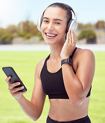 Image showing Headphones, fitness and smartphone with woman listening to motivation podcast or music outdoor on sports field with portrait. Athlete girl with 5g cellphone and audio for workout training or exercise